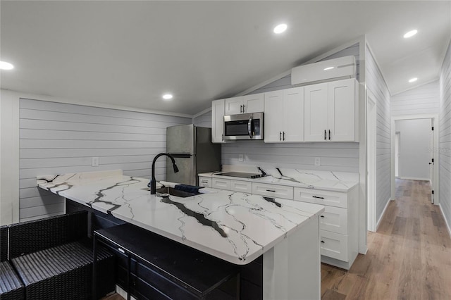 kitchen with a wall unit AC, light stone countertops, vaulted ceiling, and appliances with stainless steel finishes