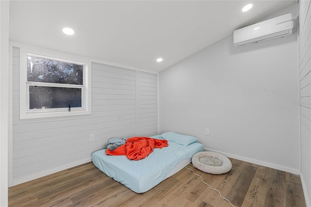 bedroom with wood-type flooring, an AC wall unit, and vaulted ceiling