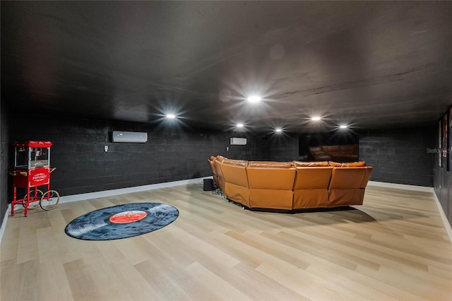 home theater room featuring a wall mounted air conditioner and light hardwood / wood-style flooring