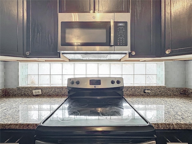 kitchen featuring dark brown cabinetry, appliances with stainless steel finishes, dark stone counters, and backsplash