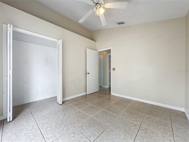 unfurnished bedroom featuring lofted ceiling, a textured ceiling, and light tile patterned floors