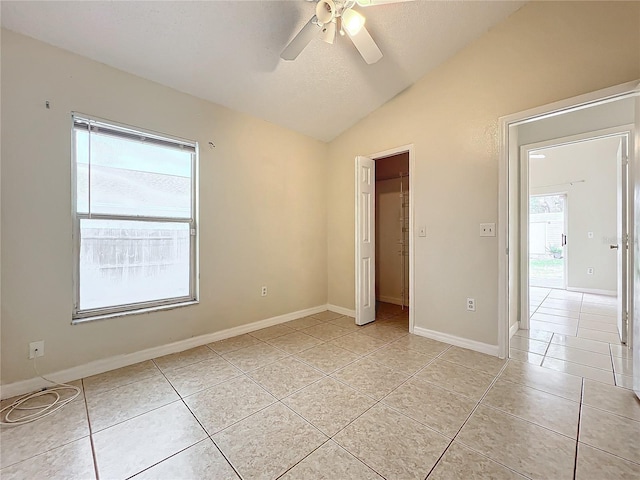 unfurnished bedroom featuring light tile patterned flooring, vaulted ceiling, a textured ceiling, a closet, and ceiling fan