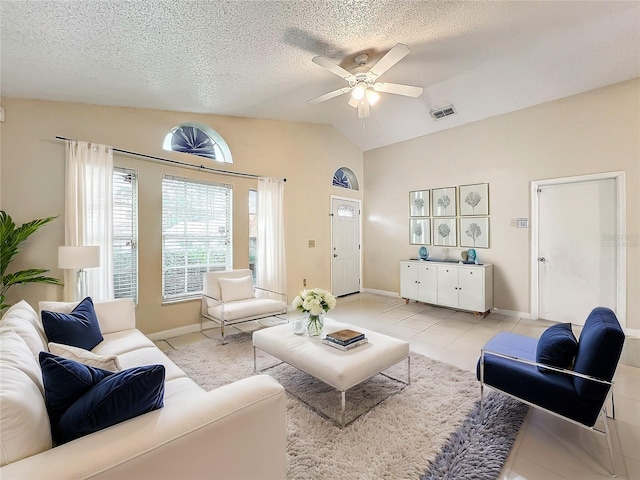 living room featuring ceiling fan, vaulted ceiling, a textured ceiling, and light tile patterned floors