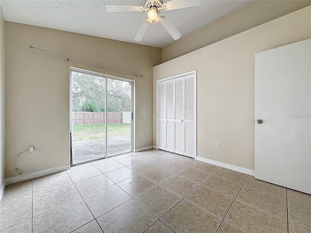 unfurnished bedroom with a textured ceiling, light tile patterned floors, a closet, ceiling fan, and access to exterior