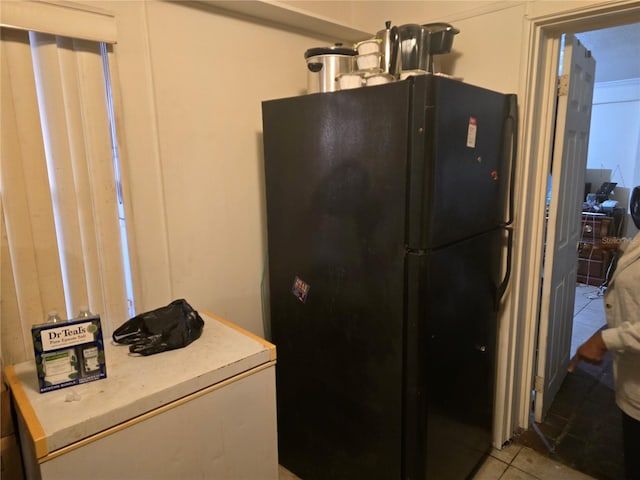 kitchen with black fridge and light tile patterned flooring