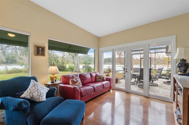 living room with french doors, lofted ceiling, and light wood-type flooring