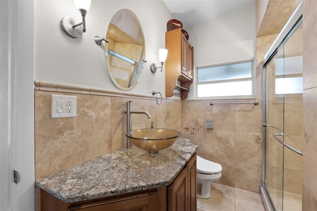 bathroom featuring vanity, a shower with door, toilet, and tile walls