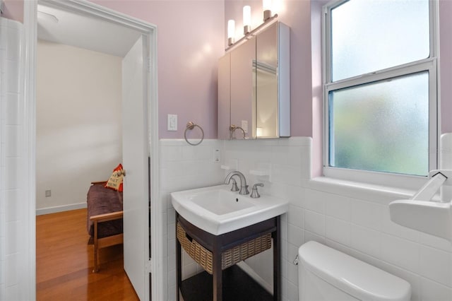 bathroom with hardwood / wood-style flooring, tile walls, and a wealth of natural light