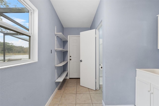 hallway featuring a wealth of natural light and light tile patterned flooring