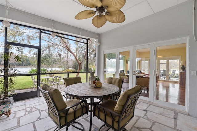 sunroom featuring ceiling fan, a water view, and french doors