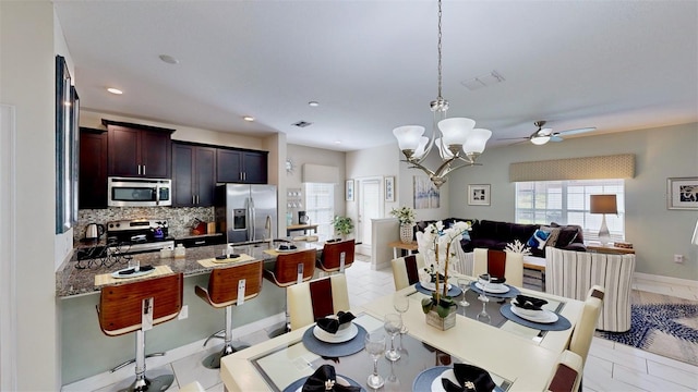 kitchen with light stone counters, pendant lighting, a breakfast bar area, decorative backsplash, and appliances with stainless steel finishes