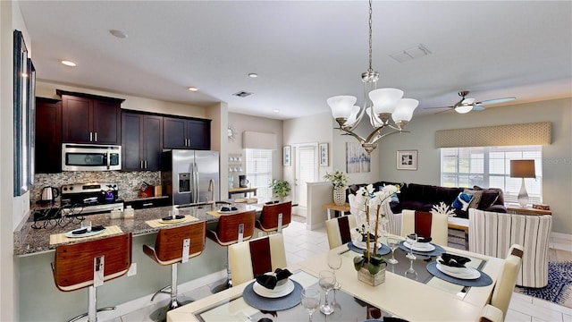 tiled dining area with ceiling fan with notable chandelier