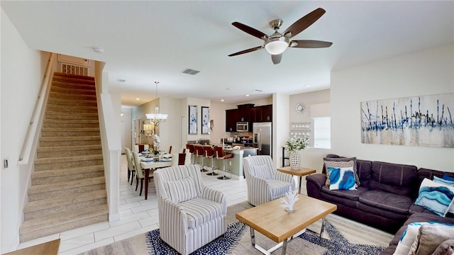 living room with ceiling fan with notable chandelier and light tile patterned flooring