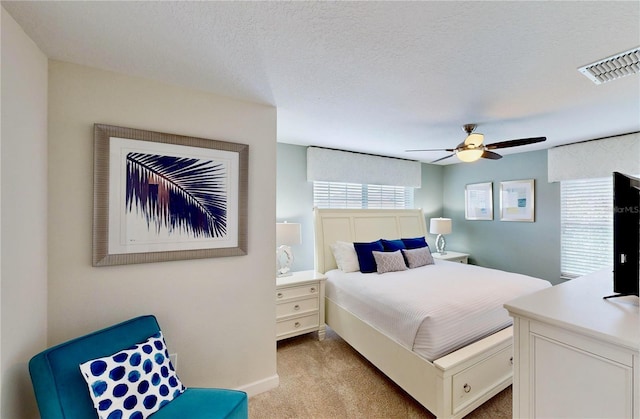 bedroom featuring a textured ceiling, ceiling fan, and light carpet