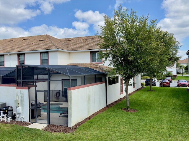 back of property featuring glass enclosure and a yard