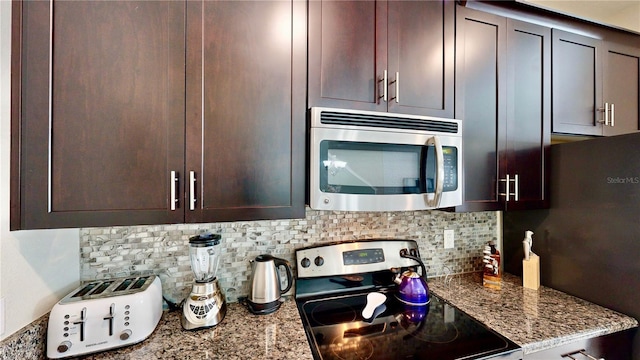 kitchen featuring decorative backsplash, dark brown cabinets, stainless steel appliances, and light stone counters