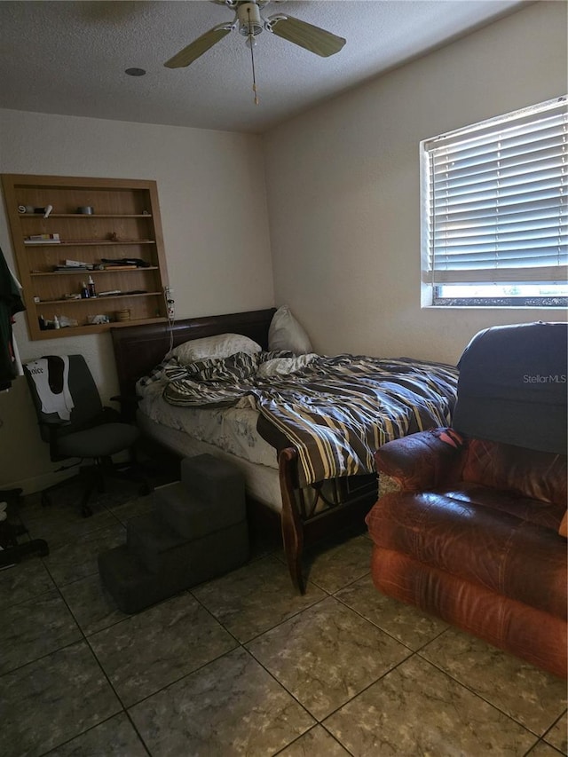 bedroom featuring ceiling fan, tile patterned flooring, and a textured ceiling