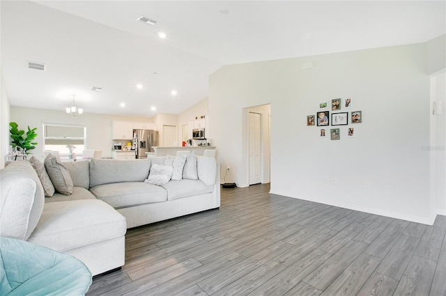 living room with light hardwood / wood-style flooring, lofted ceiling, and an inviting chandelier