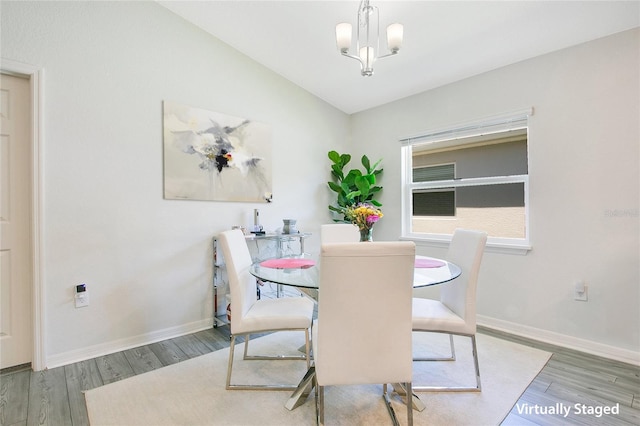 dining area featuring hardwood / wood-style floors, vaulted ceiling, and an inviting chandelier