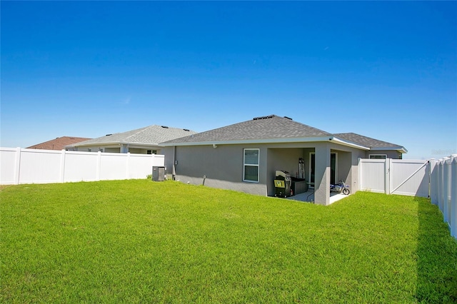 rear view of house with central air condition unit and a yard