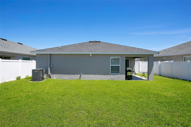 rear view of property featuring central AC unit and a lawn