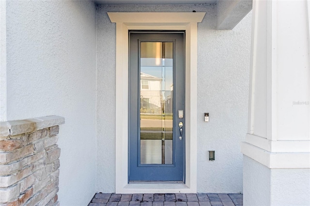 doorway to property featuring stucco siding