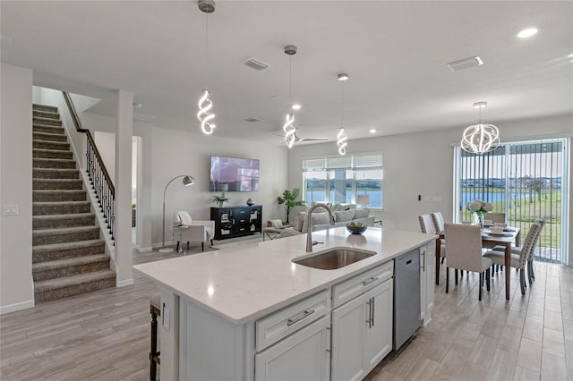 kitchen with open floor plan, a center island with sink, a sink, and decorative light fixtures