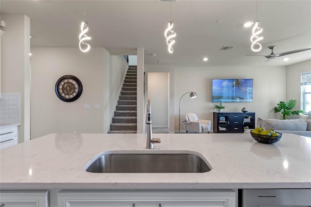 kitchen with open floor plan, light stone counters, and decorative light fixtures