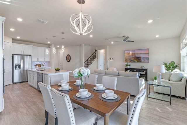 dining area featuring recessed lighting, visible vents, stairway, light wood-style floors, and ceiling fan with notable chandelier