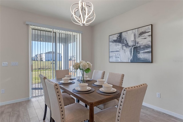 dining area featuring baseboards, an inviting chandelier, and light wood-style floors