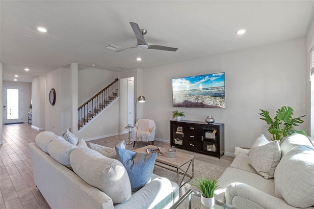 living room featuring light wood finished floors, visible vents, baseboards, stairway, and recessed lighting