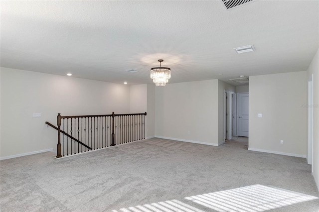 empty room featuring light carpet, a notable chandelier, visible vents, and baseboards