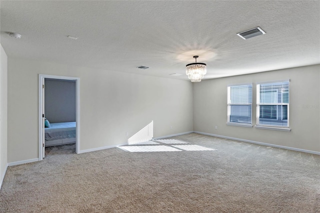 empty room with a chandelier, visible vents, light carpet, and baseboards