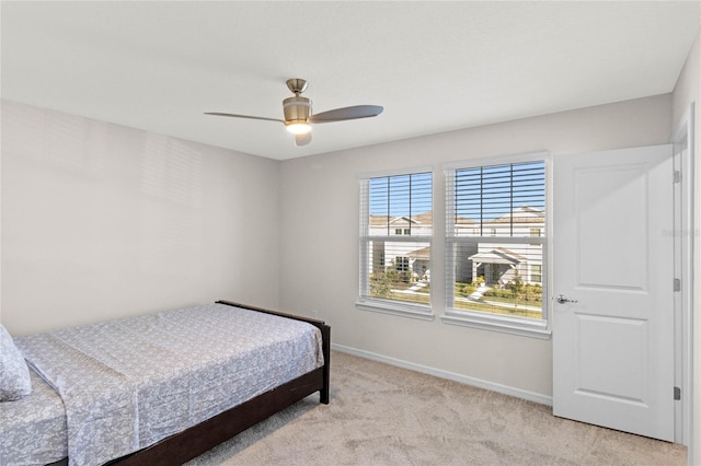 bedroom with a ceiling fan, light colored carpet, and baseboards