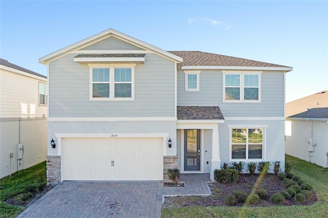 view of front of property with decorative driveway, stucco siding, a shingled roof, an attached garage, and stone siding