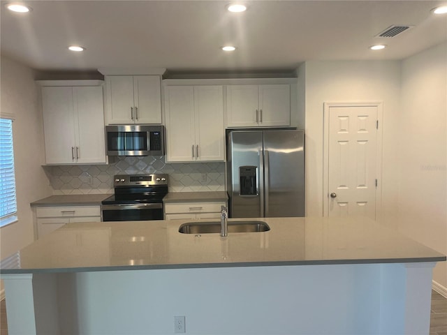 kitchen with a large island with sink, white cabinetry, sink, and appliances with stainless steel finishes