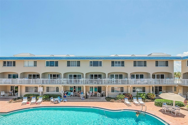 back of house with a community pool and a patio