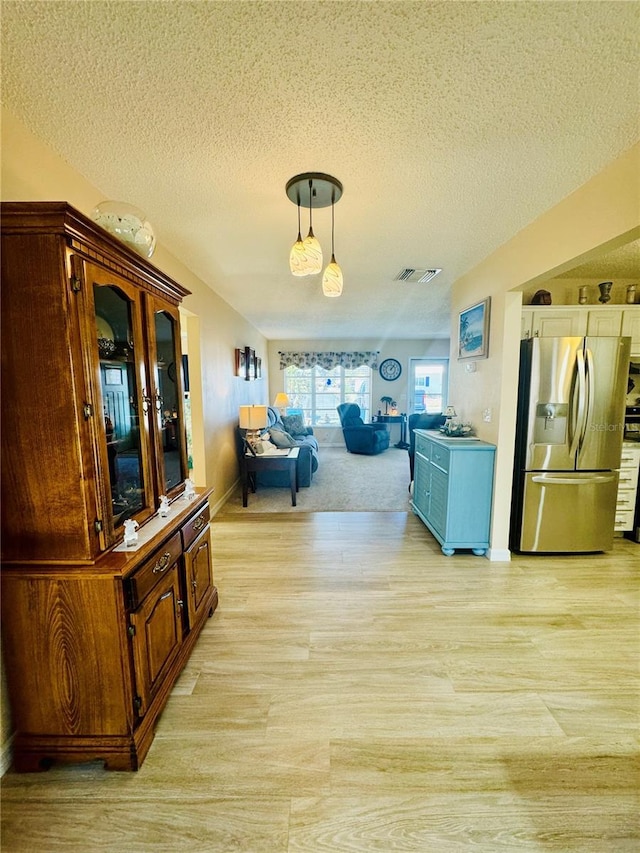 corridor featuring a textured ceiling and light hardwood / wood-style floors