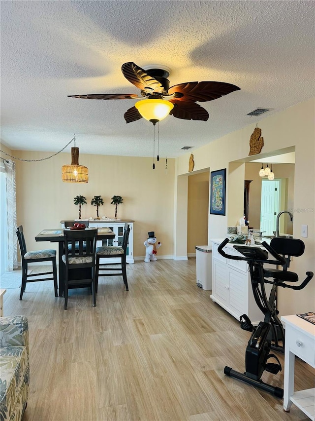 dining area with ceiling fan, a textured ceiling, and light hardwood / wood-style floors