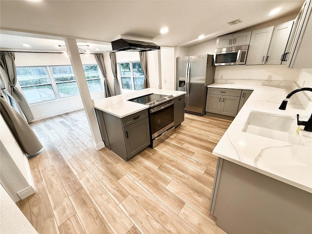 kitchen with light stone countertops, gray cabinetry, stainless steel appliances, extractor fan, and sink