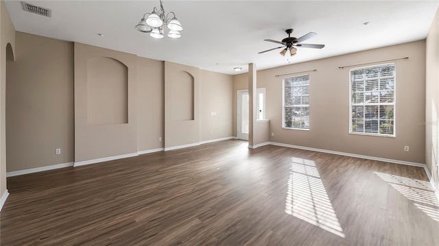 empty room with visible vents, arched walkways, baseboards, and dark wood-style floors