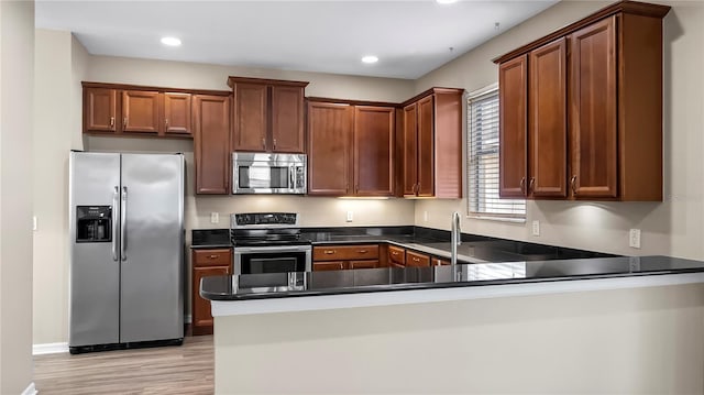 kitchen featuring dark countertops, recessed lighting, a peninsula, and stainless steel appliances