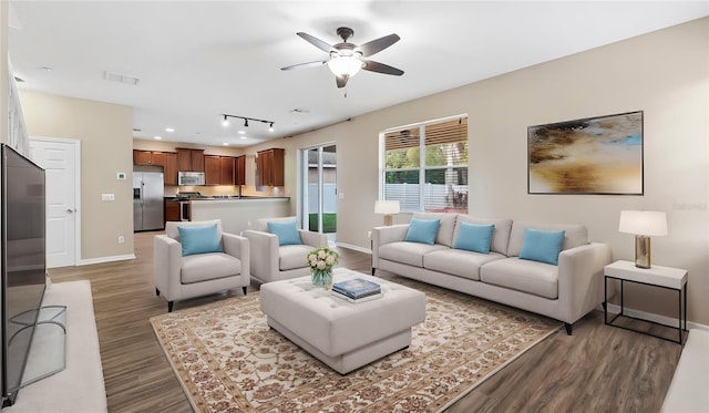 living room with ceiling fan, wood finished floors, visible vents, and baseboards