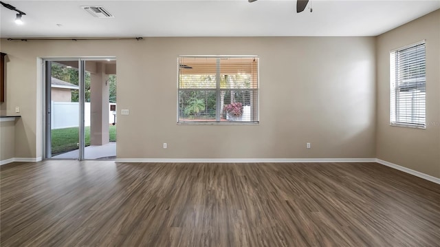 spare room featuring dark wood-style floors, visible vents, a ceiling fan, and baseboards