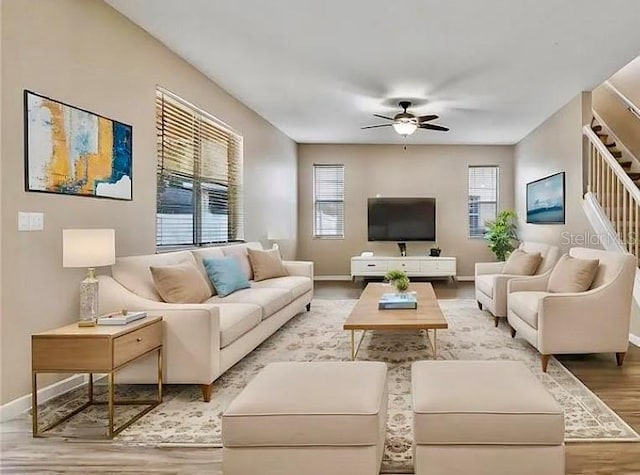 living room with a ceiling fan, a healthy amount of sunlight, light wood-type flooring, and baseboards