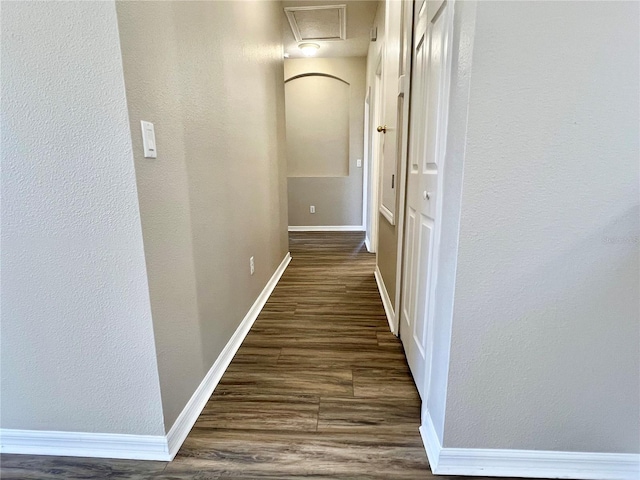 hallway featuring baseboards and dark wood finished floors