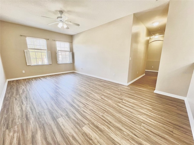 unfurnished room featuring baseboards, wood finished floors, a textured ceiling, and ceiling fan