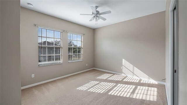 empty room with carpet flooring, baseboards, and ceiling fan