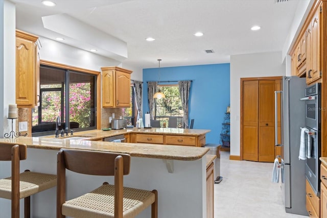 kitchen featuring kitchen peninsula, tasteful backsplash, hanging light fixtures, and a breakfast bar area