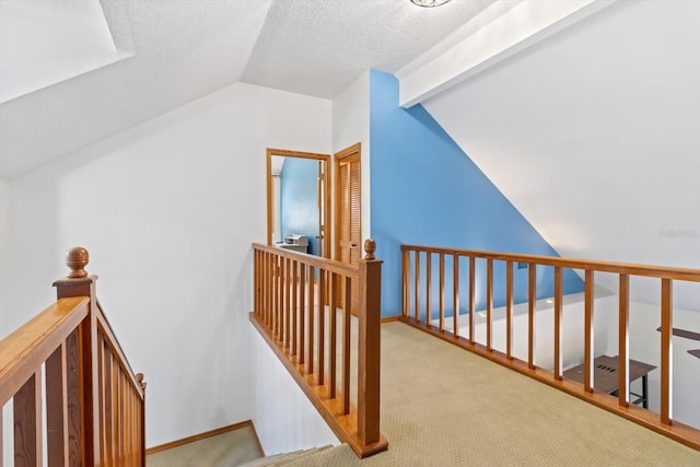 hallway with light carpet, a textured ceiling, and lofted ceiling with beams